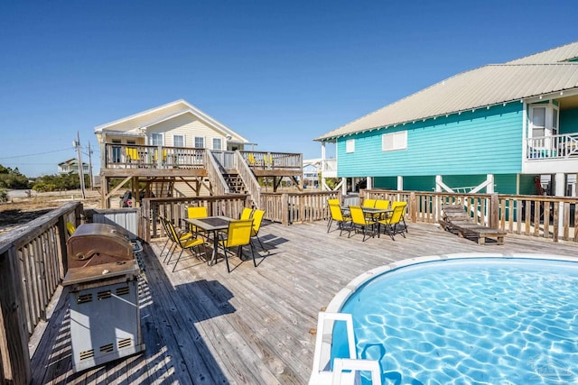 view of swimming pool featuring outdoor dining space, area for grilling, and a wooden deck