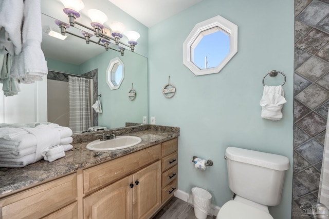 full bath with baseboards, a shower with shower curtain, toilet, wood finished floors, and vanity