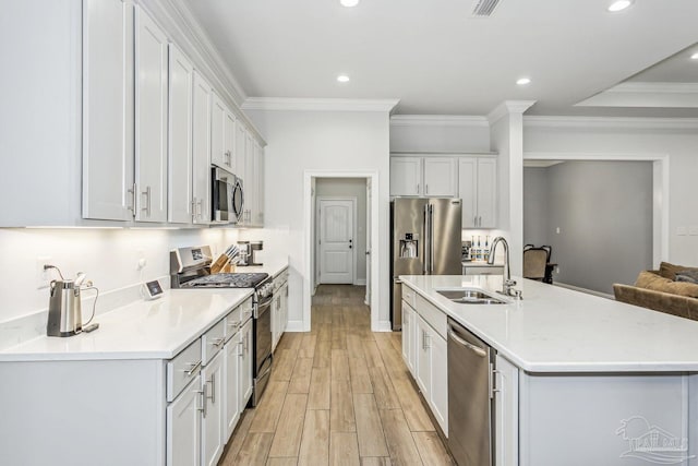 kitchen with recessed lighting, light countertops, a sink, light wood finished floors, and appliances with stainless steel finishes