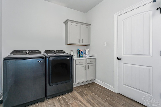clothes washing area with baseboards, dark wood-style flooring, cabinet space, and washing machine and clothes dryer