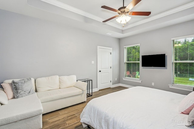 bedroom featuring crown molding, multiple windows, wood finished floors, and a raised ceiling