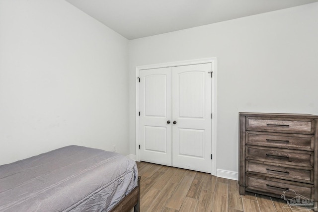 bedroom featuring baseboards, wood finished floors, and a closet