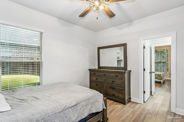 bedroom with baseboards, ceiling fan, multiple windows, and light wood-style flooring