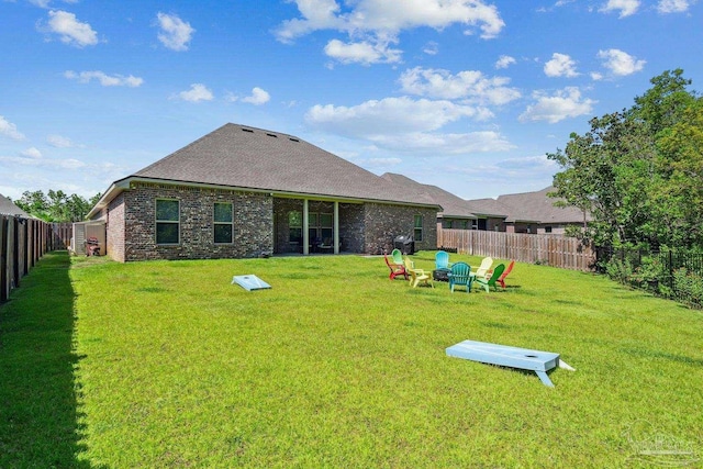 rear view of property with a fenced backyard, a shingled roof, and a yard