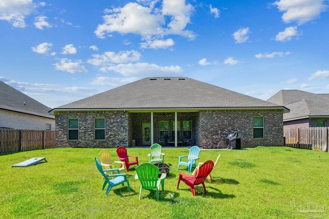 rear view of property featuring a fenced backyard, a yard, and brick siding