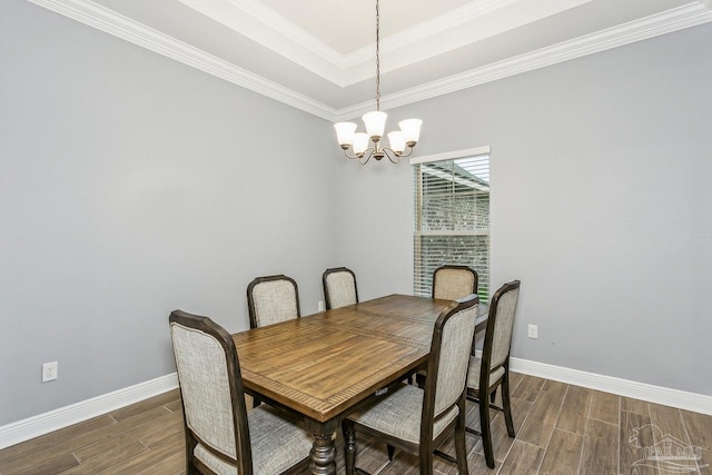 dining room featuring a notable chandelier, a raised ceiling, baseboards, dark wood-type flooring, and ornamental molding