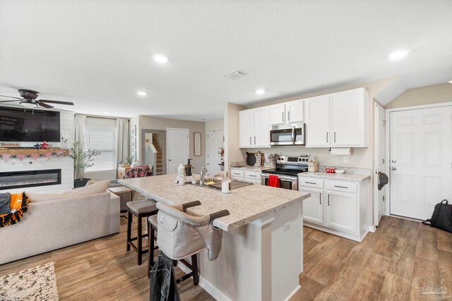 kitchen with ceiling fan, stainless steel appliances, white cabinets, sink, and light hardwood / wood-style floors