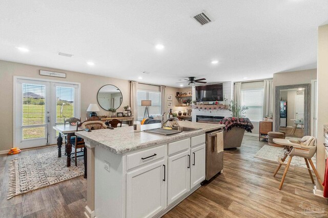 kitchen featuring stainless steel dishwasher, white cabinetry, ceiling fan, hardwood / wood-style floors, and an island with sink