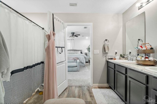 bathroom featuring dual vanity, ceiling fan, and wood-type flooring