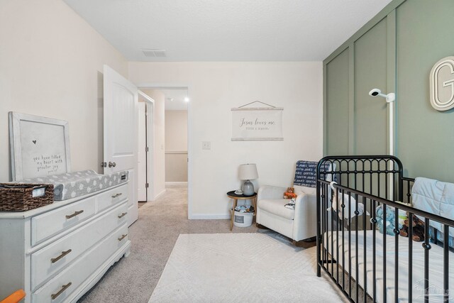 bedroom with a nursery area and light colored carpet