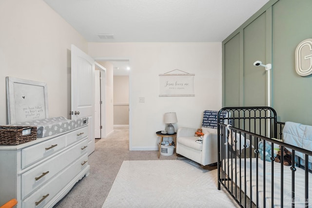 bedroom with light carpet, a crib, visible vents, and baseboards