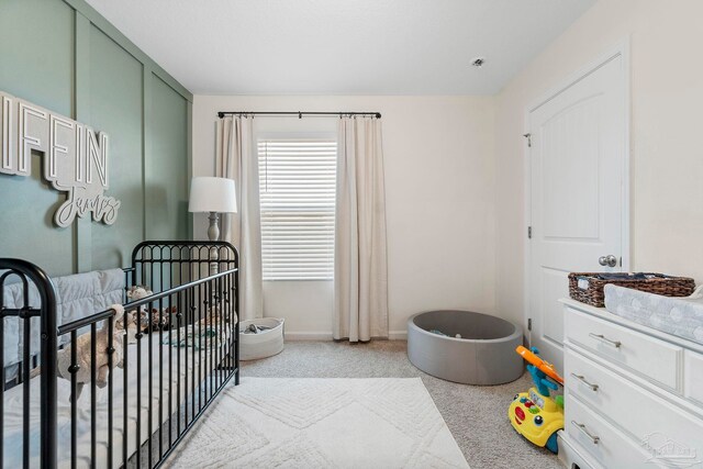 bedroom featuring a nursery area and light colored carpet