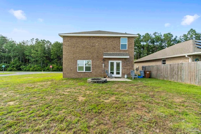 rear view of house featuring an outdoor fire pit, french doors, fence, a yard, and brick siding