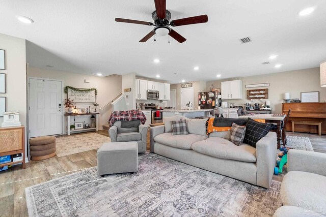 living room with light hardwood / wood-style flooring and ceiling fan