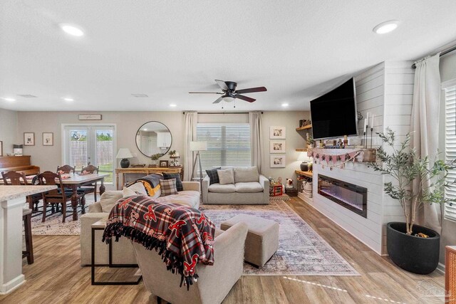 living room featuring light hardwood / wood-style floors, a textured ceiling, and ceiling fan