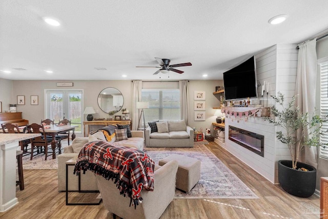 living area featuring light wood-style floors, recessed lighting, a fireplace, and a textured ceiling