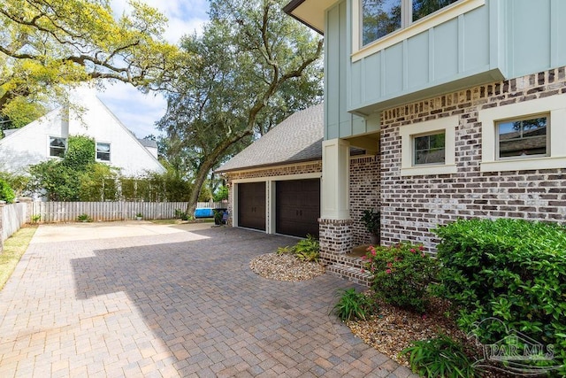 2 Bayou Blvd, Pensacola, FL 32503 - view of home's exterior with fence, an attached garage, brick siding, board and batten siding, and decorative driveway