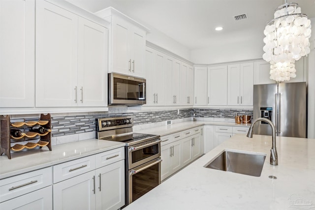 kitchen featuring white cabinetry, appliances with stainless steel finishes, sink, and hanging light fixtures