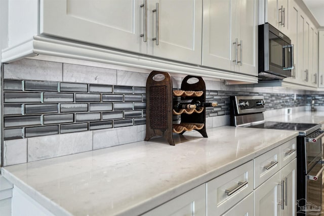 kitchen with white cabinetry, light stone countertops, stainless steel range with electric stovetop, and decorative backsplash