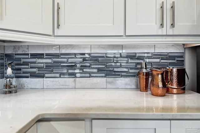 interior details with light stone countertops, white cabinetry, and tasteful backsplash