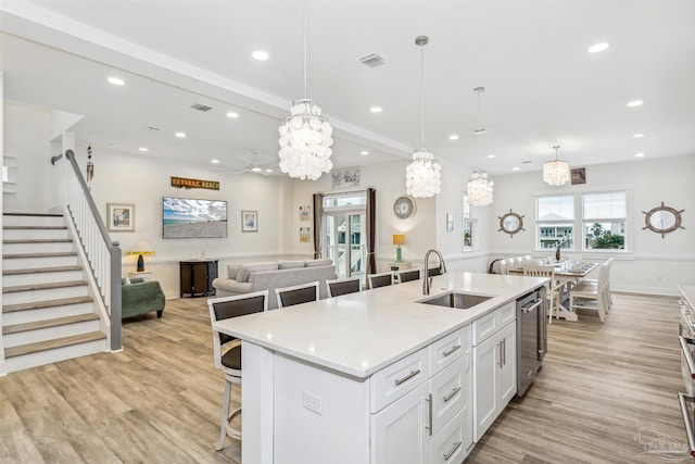 kitchen with sink, a large island, white cabinetry, decorative light fixtures, and light hardwood / wood-style flooring