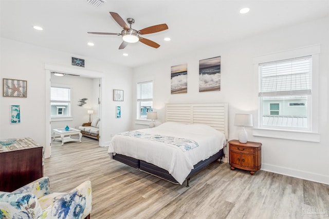 bedroom with ceiling fan, multiple windows, and light wood-type flooring