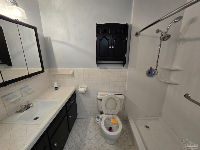 bathroom with toilet, a shower, tile walls, vanity, and tile patterned flooring