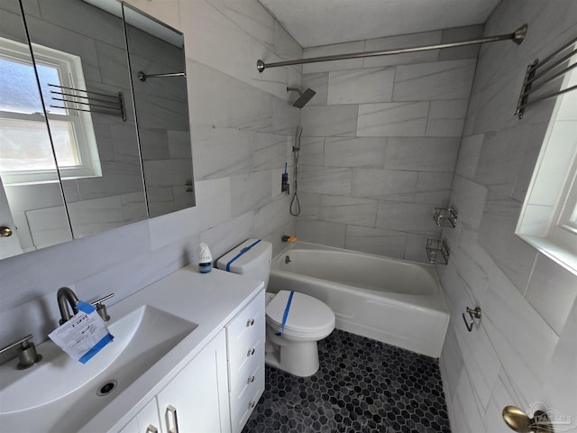 full bathroom featuring vanity, toilet, tiled shower / bath combo, and tile walls