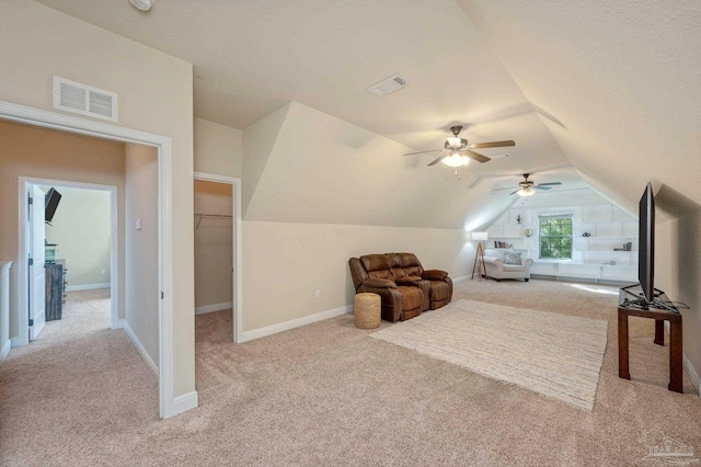 bedroom with a spacious closet, a closet, light carpet, ceiling fan, and vaulted ceiling