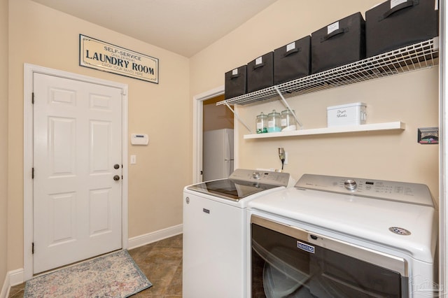 clothes washing area featuring water heater, washing machine and clothes dryer, and dark tile patterned floors