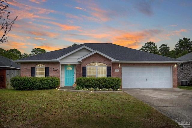 ranch-style home with a lawn, central AC unit, and a garage