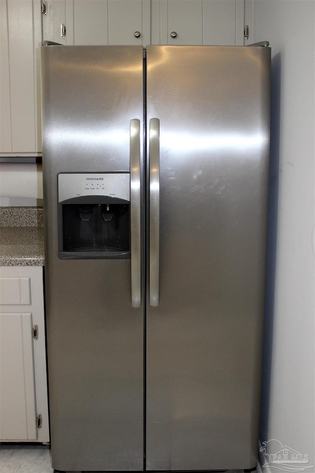 room details featuring stainless steel fridge with ice dispenser and white cabinets