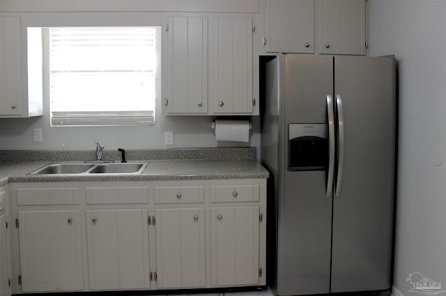 kitchen with stainless steel refrigerator with ice dispenser, sink, and white cabinets