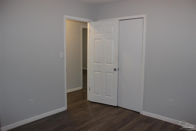 unfurnished bedroom with dark hardwood / wood-style floors and a closet