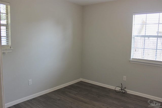 empty room with dark hardwood / wood-style floors and a healthy amount of sunlight