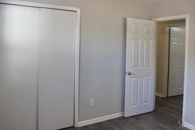 unfurnished bedroom featuring dark wood-type flooring and a closet