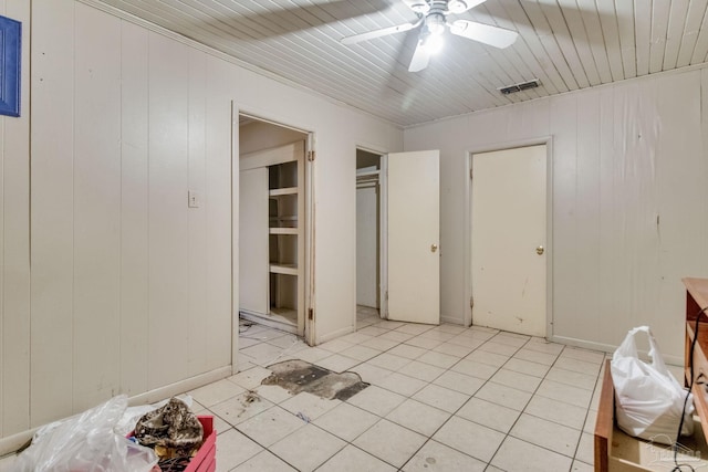 unfurnished bedroom with visible vents, wood walls, light tile patterned floors, wooden ceiling, and a ceiling fan