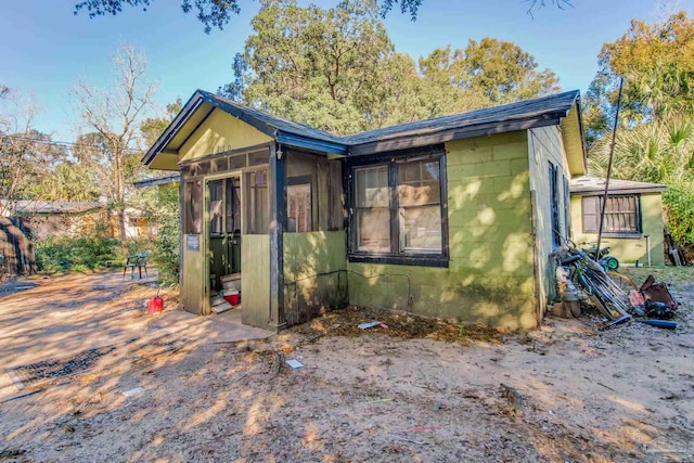 view of side of property featuring concrete block siding and a sunroom