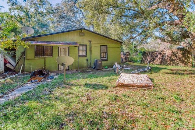 back of house featuring cooling unit, a lawn, and concrete block siding