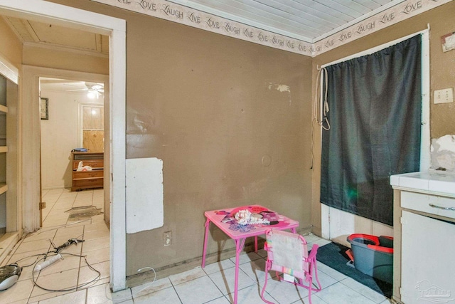 recreation room featuring ceiling fan, light tile patterned flooring, and crown molding