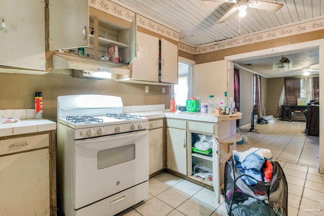 kitchen with tile countertops, wood ceiling, white gas range, light tile patterned floors, and a ceiling fan