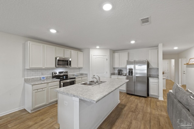 kitchen featuring sink, stainless steel appliances, white cabinetry, and an island with sink