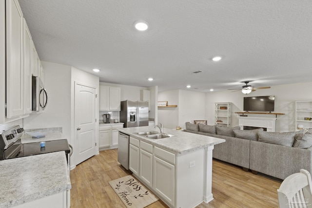 kitchen with sink, a center island with sink, appliances with stainless steel finishes, and white cabinetry