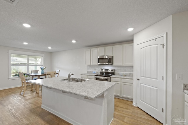 kitchen featuring a center island with sink, decorative backsplash, white cabinets, appliances with stainless steel finishes, and sink