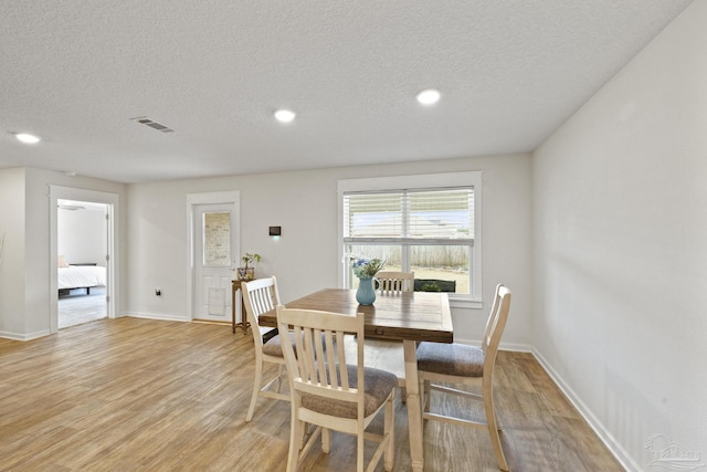 dining area with a textured ceiling and light wood-type flooring