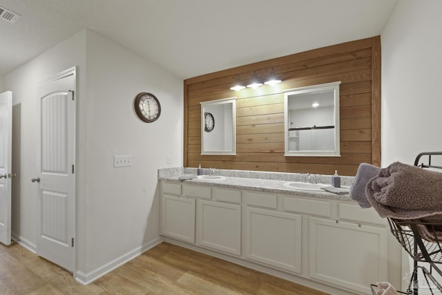 bathroom with wood-type flooring, vanity, and wood walls