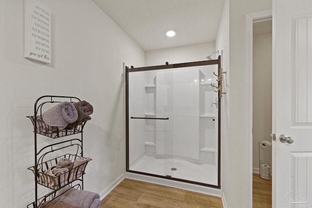 bathroom featuring a shower with door, a textured ceiling, and hardwood / wood-style flooring