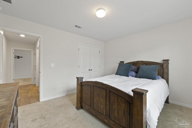 carpeted bedroom with a closet and a textured ceiling