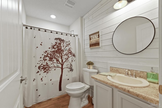 bathroom featuring vanity, wood walls, hardwood / wood-style floors, and a textured ceiling