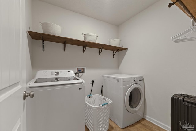 clothes washing area with separate washer and dryer, light wood-type flooring, and radiator